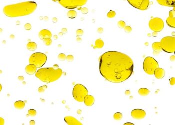 Yellow oil droplets dispersed on a white background.