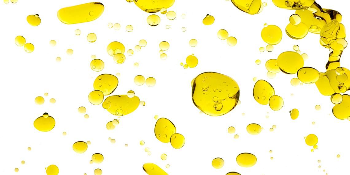 Yellow oil droplets dispersed on a white background.