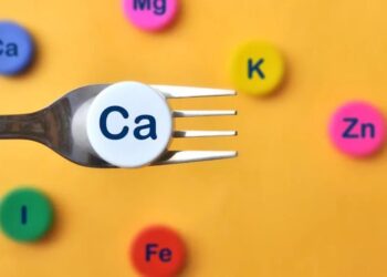 A fork with a calcium symbol on it surrounded by colorful periodic table element symbols representing different nutrients.