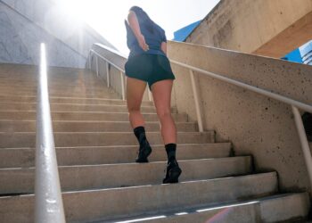 Person in athletic wear climbing outdoor staircase in an urban setting with the sun shining brightly.
