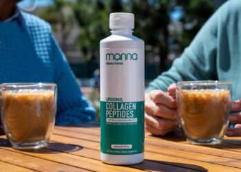 A bottle of liposomal collagen peptides supplement sits on a wooden table between two people holding glasses of iced coffee.