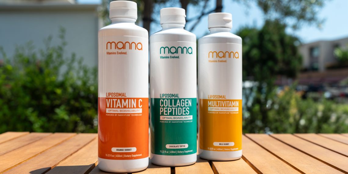 Three bottles of liposomal supplements on a wooden table: Vitamin C (orange), Collagen Peptides (green), and Multivitamin (yellow). Trees and buildings are blurred in the background.